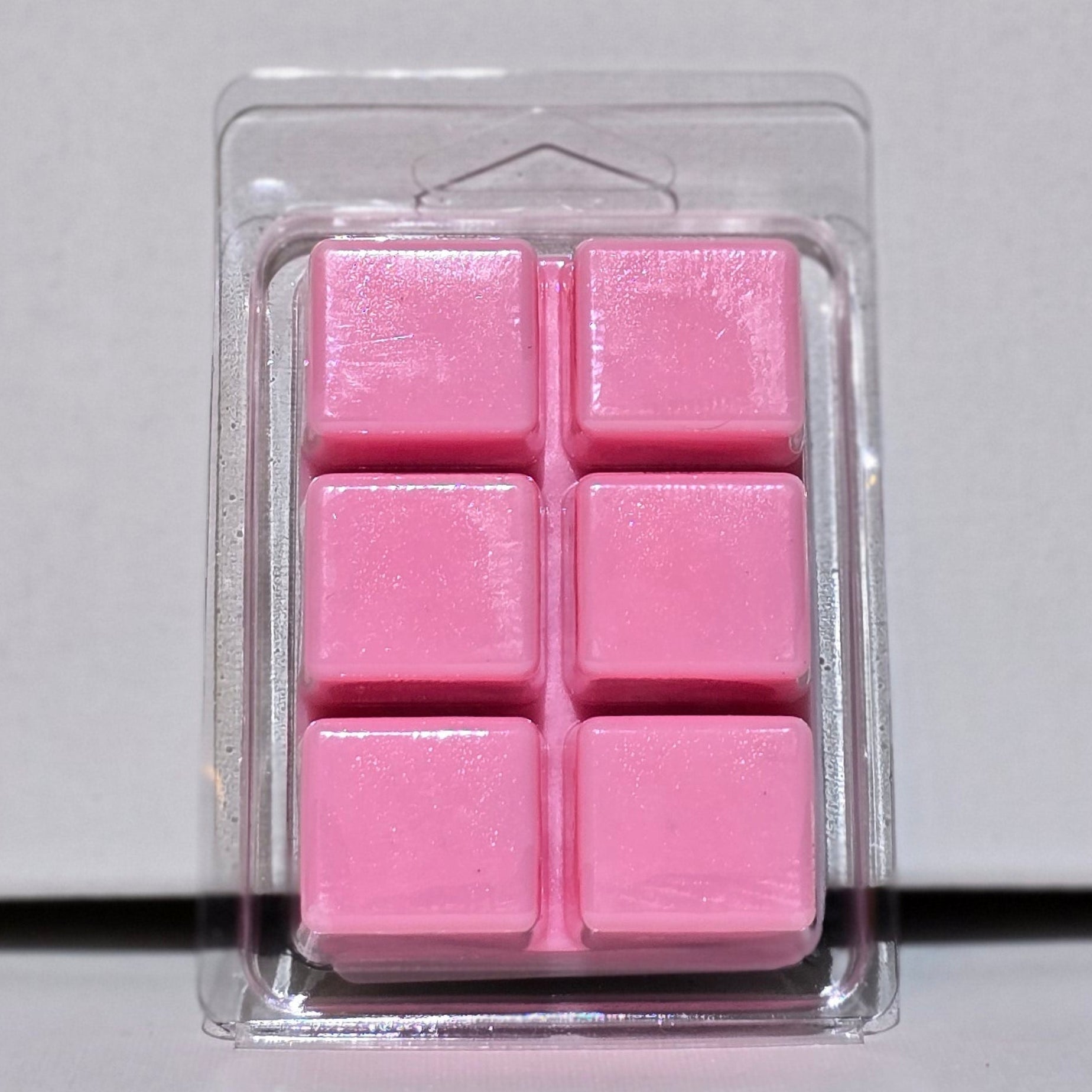 Pink wax melts in a clear plastic packaging on a light gray background